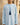 Boy in ice-blue Emirati kandura, beige stone wall