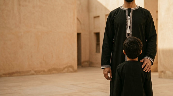 Father and son in matching black Moroccan thobes, beige courtyard
