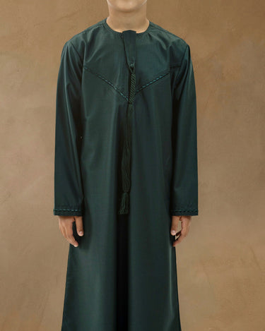 Young boy wearing a deep forest green Emirati thobe with a hanging braided tassel and chevron chest embroidery. - view 2