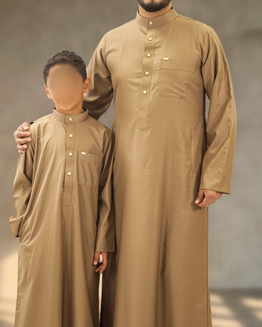 A man and young boy wearing matching tan band collar Saudi thobes.