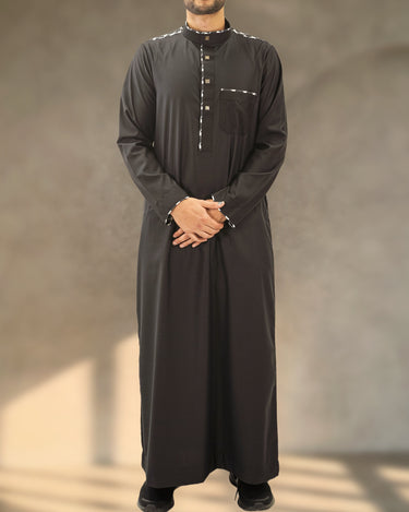Front view of the Tarout men's black Saudi thobe with patterned shoulder trim and metallic placket buttons. - view 2